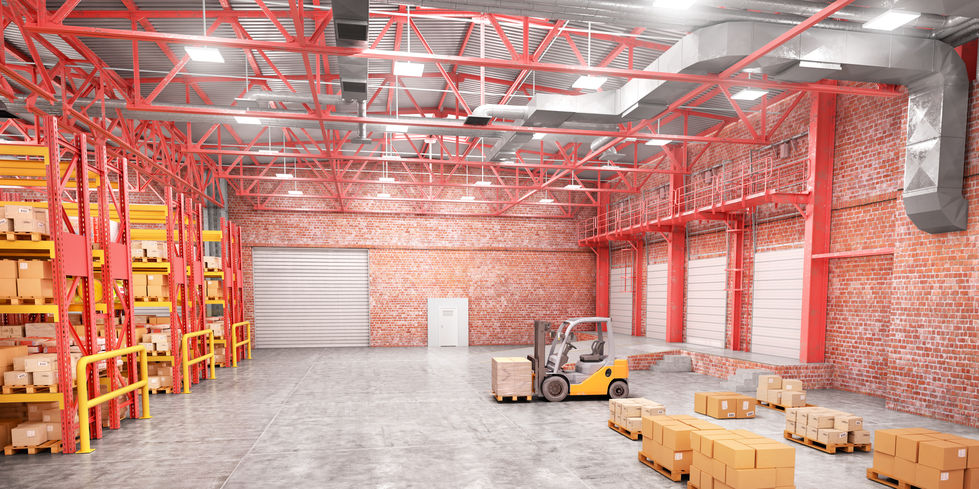 Forklift moving boxes in a spacious warehouse with red beams, brick walls, and shelves stocked with boxes.